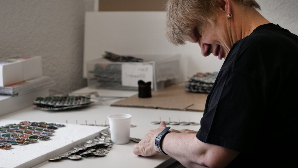 Mitarbeitende der Talentwerkstatt bei der Herstellung der Scheiben aus Kaffeekapseln.