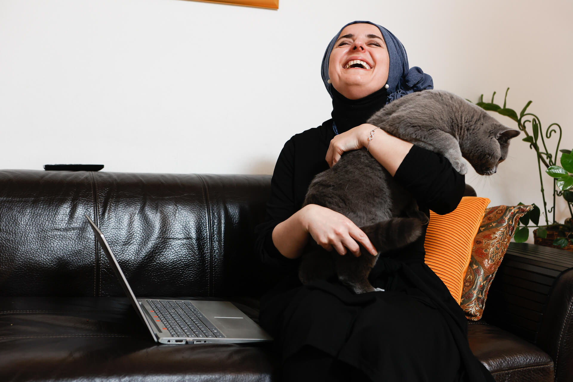 Eine starkt sehbeeinträchtigte Frau sitzt auf ihrem Sofa beim Interview und lacht aus vollem Herzen und voll Zuversicht.