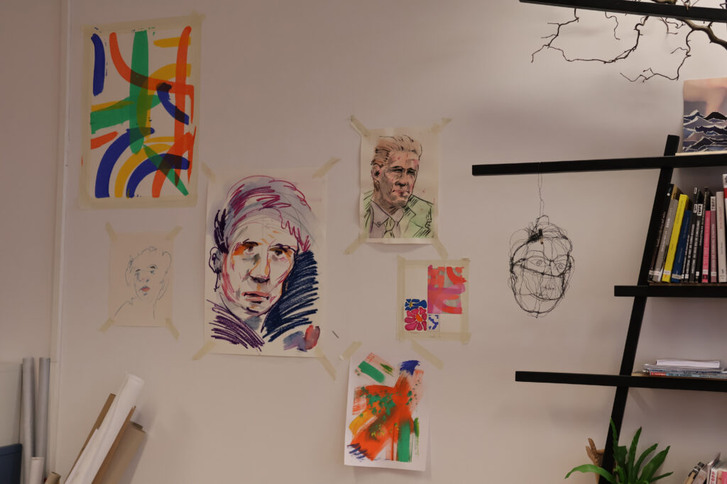 Wand mit Bildern von Künstler:innen aus dem Tageszentrum.